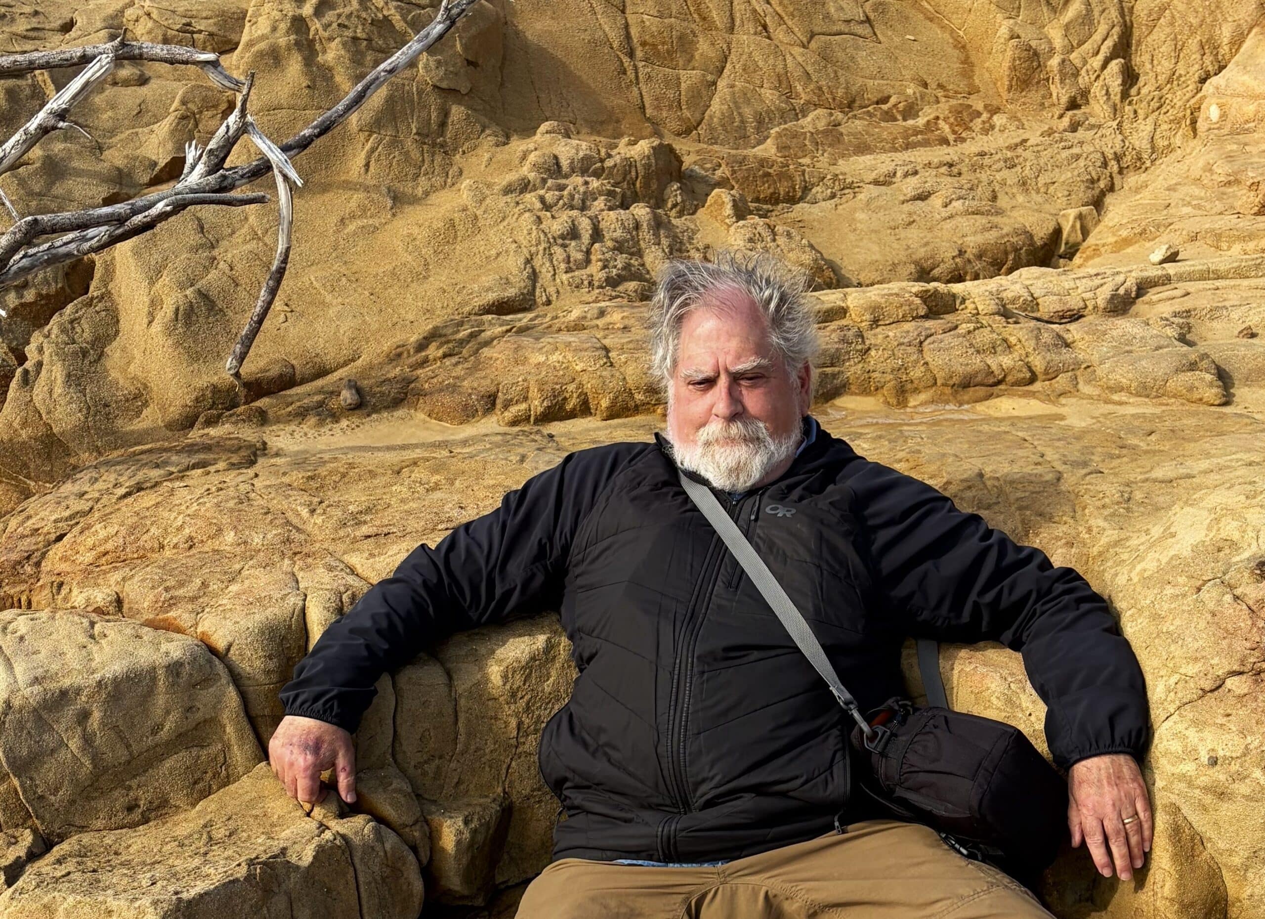 Writer, photographer, naturalist Stephen Nett seated on a rock outcrop along the wild Sonoma Coast of California.